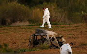 Forensic experts walk in a field after a powerful bomb blew up a car (Foreground) and killed investigative journalist Daphne Caruana Galizia in Bidnija, Malta, October 16, 2017. 