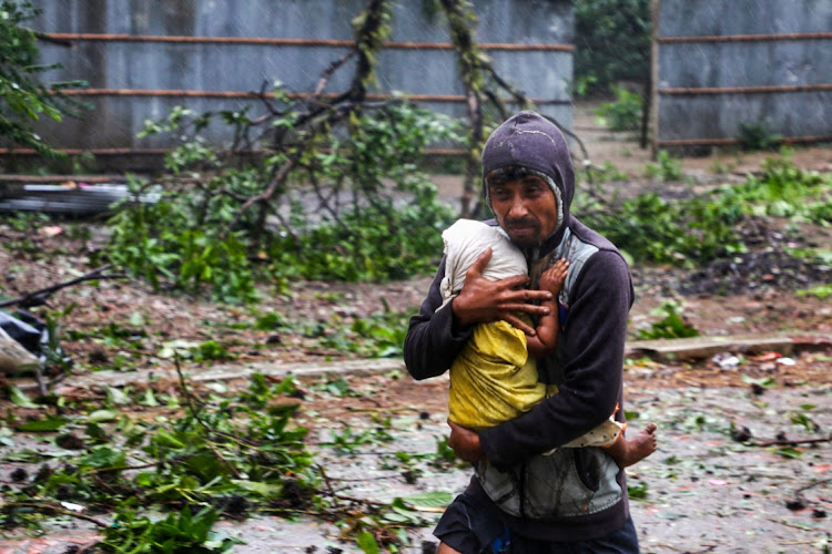 A man holds a child as he moves to the nearest cyclone shelter at Shah Porir Dwip during the landfall of Cyclone Mocha in Teknaf, Bangladesh, on May 14 2023. Picture: REUTERS/JIBON AHMED