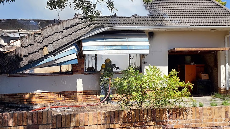 A firefighter extinguishes a blaze at the Paarl home of an 82-year-old wheel-chair bound woman. Sadly, she perished in the fire.