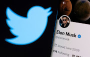 Elon Musk's Twitter account is seen on a smartphone in front of the Twitter logo. File Photo