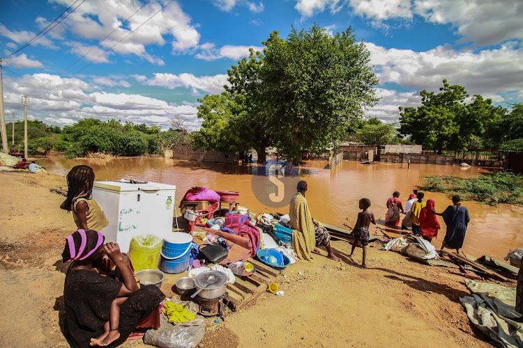 Women wade through water to salvage their belongings from Mororo village in Madogo after Tana River burst its banks on April 27,2024.