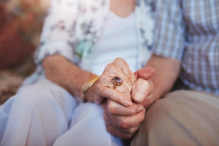 elderly couple holding hand.