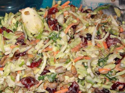 broccoli, seeds, dried cranberries, brussels sprouts, carrots, onion, kale in a salad.