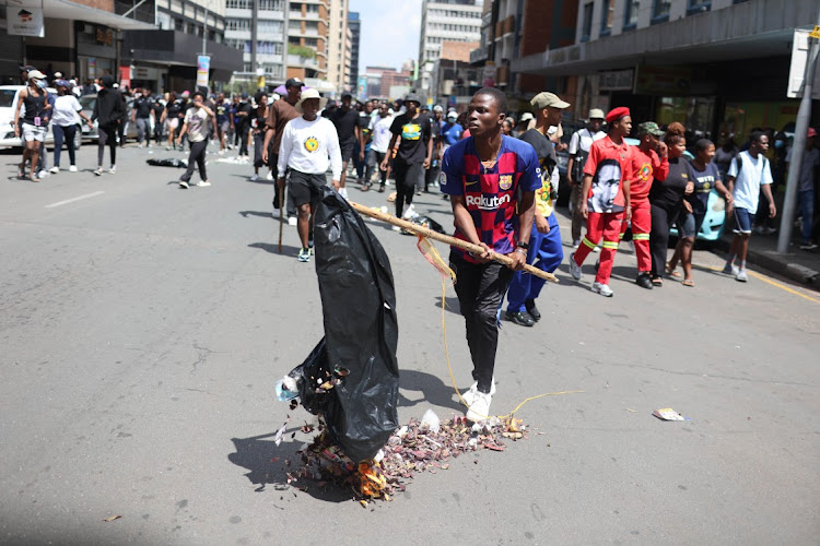 A protesting student empties a bin on the streets of Braamfontein, Johannesburg, near the University of the Witwatersrand on March 2 2023.