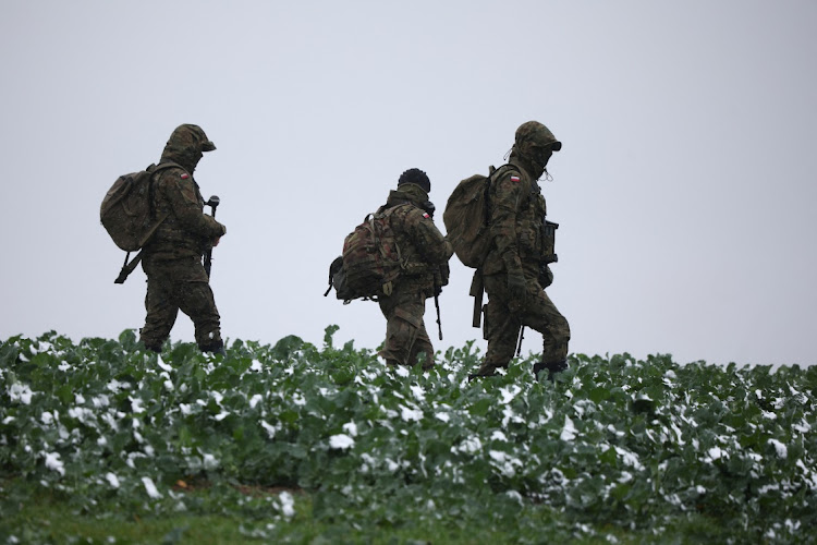 Polish soldiers walk in the field near the site of an explosion in Przewodow, a village in eastern Poland near the border with Ukraine, November 17, 2022.