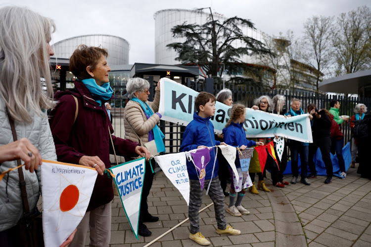 Supporters hold banners as they arrive for the ruling in the climate case Verein KlimaSeniorinnen Schweiz and Others v Switzerland, at the European Court of Human Rights in Strasbourg, France, April 9 2024. The slogan reads "Climate justice". Picture: REUTERS/Christian Hartmann