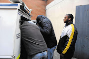 Crime intelligence officer Captain Morris Tshabalala tries to avoid photographers after appearing in the Sasolburg Magistrate's Court in connection with a cash-in-transit heist. His co-accused Sipho Motsamayi and Mapotswe Moloi (brown jacket) wait to get into the police van