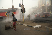 The fire department clears away debris that was set alight during a protest in Pietermaritzburg on Tuesday night.