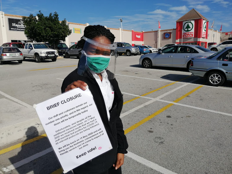 A Newton Park SUPERSPAR worker stands in the parking lot advising shoppers that the store has been temporarily closed as a result of a staff member testing positive for Covid-19
