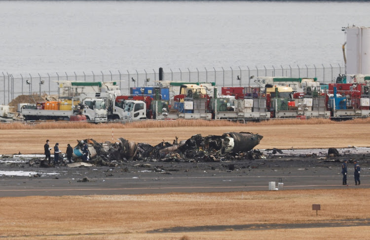 Officials investigate a burnt Japan Coast Guard aircraft after a collision with Japan Airlines' Airbus A350 plane at Haneda International Airport in Tokyo, Japan, on January 3 2024.