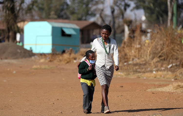 A woman walks with her daughter as schools reopen amid a nationwide coronavirus disease (COVID-19) lockdown in Eikenhof, south of Johannesburg, South Africa August 24 2020.