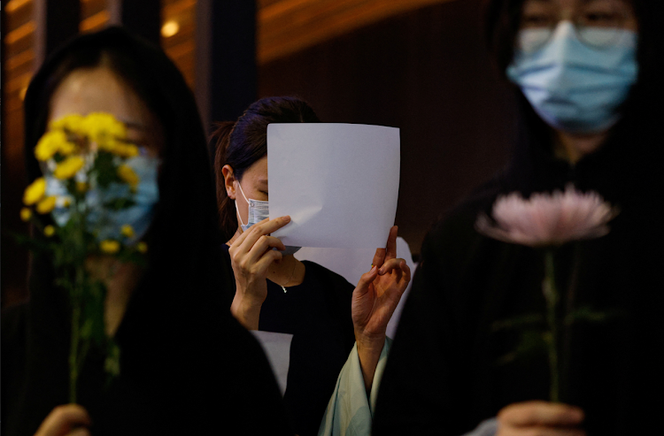 A woman holds a white sheet of paper in protest over coronavirus disease (Covid-19) restrictions in mainland China, during a commemoration of the victims of a fire in Urumqi, in Hong Kong, China on November 28, 2022.