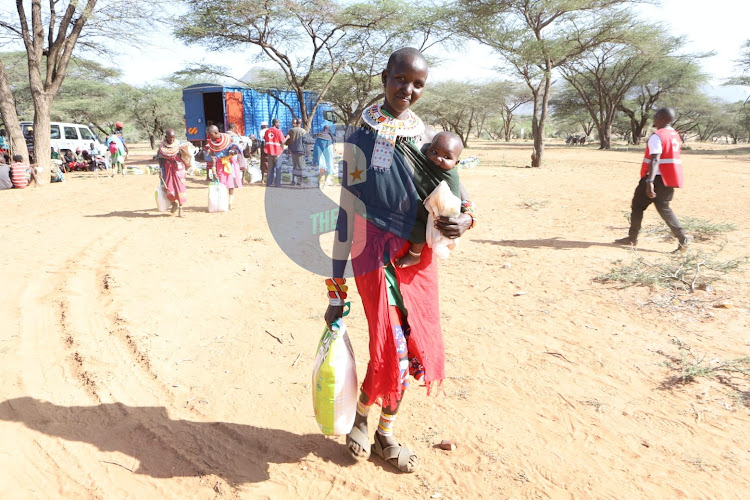 A woman carries her package during food distribution exercise by Red Cross at Lenguruma Village, Isiolo North on January 14, 2023