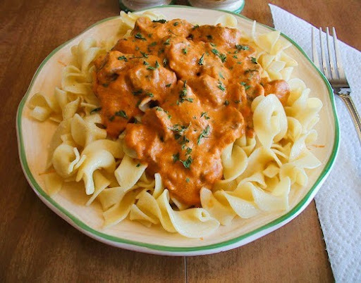 Photo of Venison Stroganoff served over cooked egg noodles.