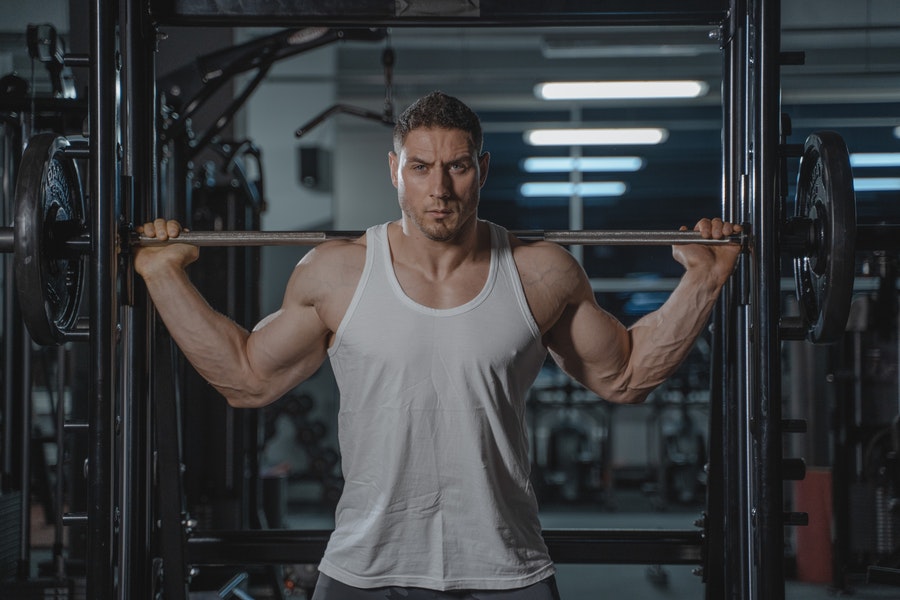 Homem malhando na academia com uma regata