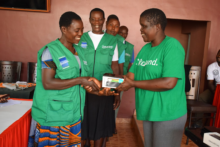 Child Fund Kenya project coordinator Mary Ochieng hands over mobile phone gadget to facilitators in Rangwe on December 17,2023