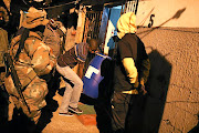 Residents  carry a drum full of homemade beer confiscated by the police in Alexandra during a patrol with troops and community leaders. / Alaister Russell