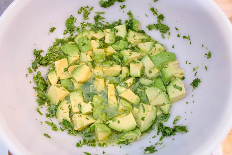 Cilantro, Lime Juice, Olive Oil, And Diced Avocado In A Bowl.