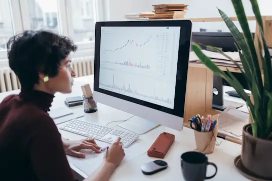 A female marketing expert looking at the screen of a computer and collecting information from the graphs and charts displayed.