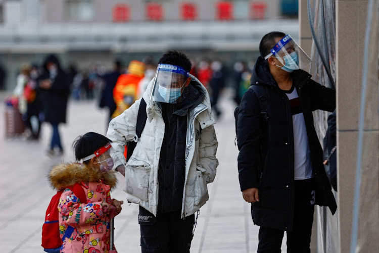 People wearing protective face shields enter the Beijing Railway Station on January 7, ahead of the Chinese Lunar New Year.