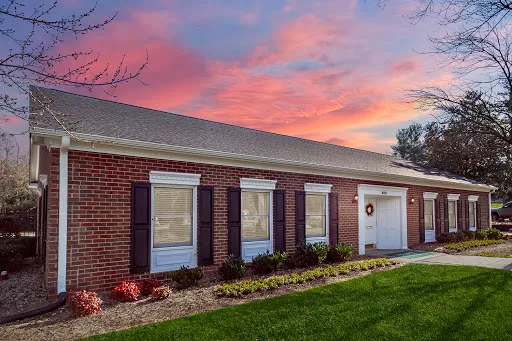 Colonial Apartments building with brick and light siding at dusk