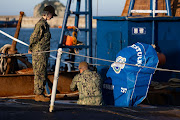 A member of the US Navy enters the hatch of USS Kentucky ballistic missile submarine in Busan, South Korea, on Wednesday, July 19, 2023.   