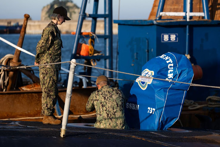 A member of the US Navy enters the hatch of USS Kentucky ballistic missile submarine in Busan, South Korea, on Wednesday, July 19, 2023.