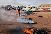 A woman walks past burning tires during clashes that erupted after a Kenyan police officer shot dead several people and himself in a rampage attack in Nairobi, Kenya, December 7, 2021.