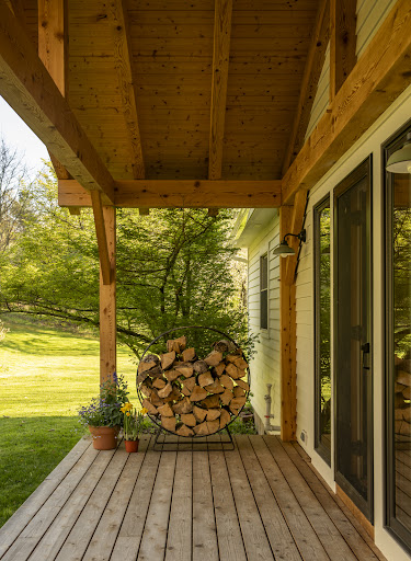 Wooden porch with decorative firewood in this luxury property for sale in East Chatham ($599,000)