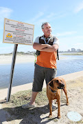 Milnerton resident Jason Smith next to a sign warning people to enter the water at their own risk.