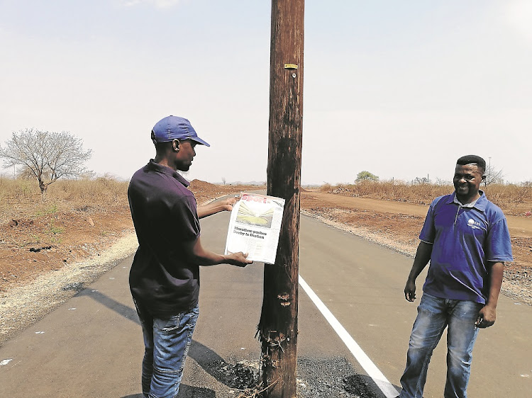 Fani Tsela, left, and William Shogole inspect the electrical pole in the middle of a newly tarred road in Limpopo.