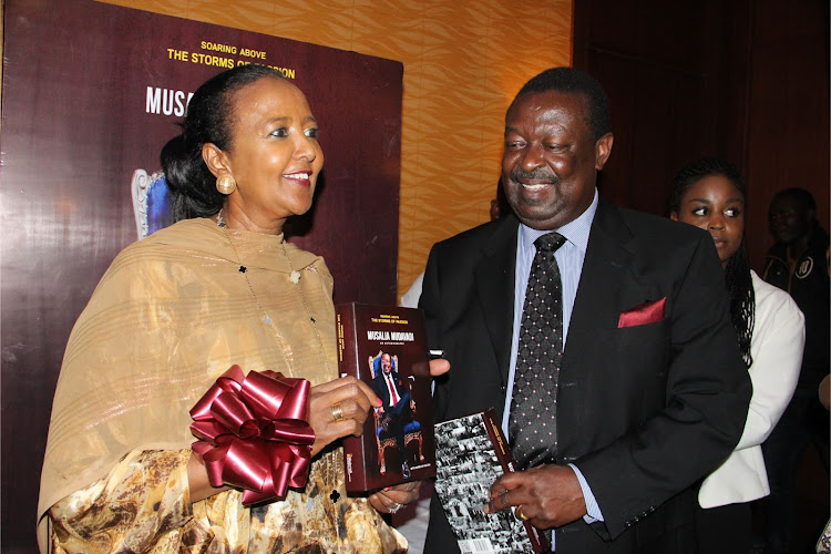 Mudavadi presents the chief guest Amina Mohamed a copy of the book