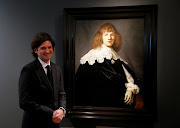 Dutch art dealer Jan Six stands next to a Rembrandt painting called 