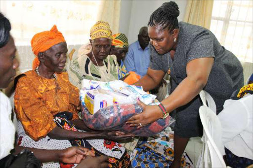 First Lady of Kisumu County Olivia Ranguma (right) presents blankets,bar soaps and foodstuffs to some of the 20 the disabled and vulnerable persons drawn from four wards of Muhoroni sub-county yesterday.Photo Maurice Alal