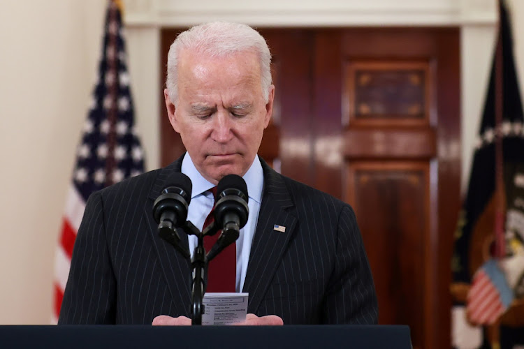 US President Joe Biden looks at his daily schedule, a card which also has an update of US deaths, during his remarks in honor of the 500,000 US deaths from the coronavirus disease (Covid-19), in the Cross Hall at the White House in Washington, US, February 22, 2021.