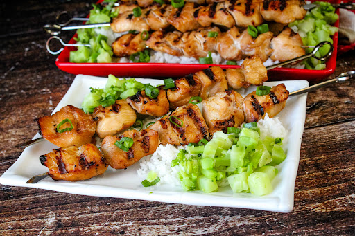 Two Teriyaki Chicken Kabobs on a plate with rice.