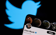 Elon Musk's Twitter account is seen on a smartphone in front of the Twitter logo .