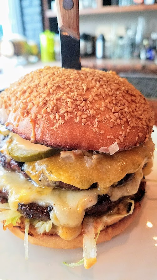 Superbite Happy Hour item Double Stack Cheeseburger with grilled ground beef and shitake, cheddar and fontina cheeses on the two patties, fancy sauce, dill pickle, onion, sesame seed bun