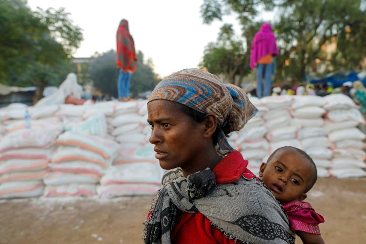 A woman carries an infant as she queues in line for food in the town of Shire, Tigray region, Ethiopia. File photo: REUTERS/BAZ RATNER