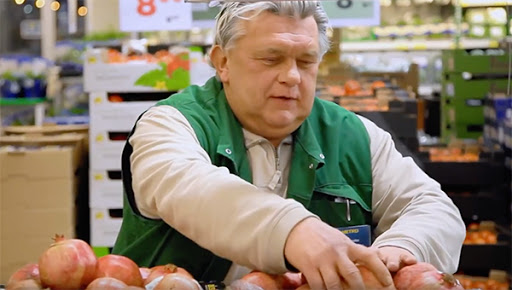 Image of a man arranging pomegranates in a retail store