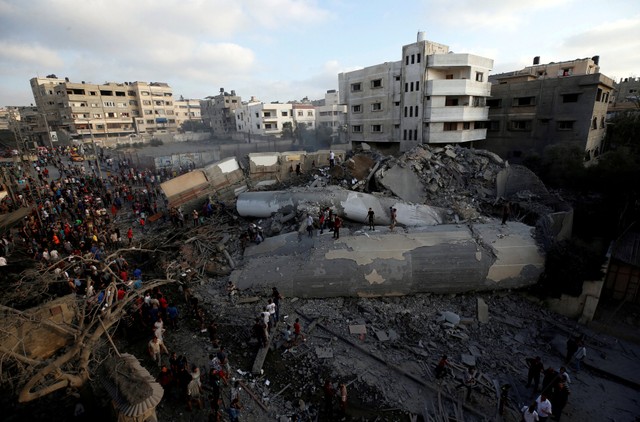 Palestinians gather around a building after it was bombed by an Israeli aircraft, in Gaza City August 9, 2018.