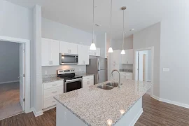 Kitchen with white shaker cabinets, granite countertops, stainless steel appliances, wood floors, pendant lights over island