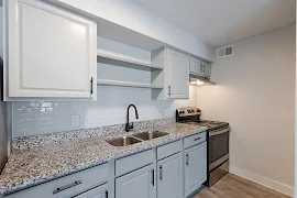 Kitchen with light colored cabinets, stone inspired countertops, light colored tile backsplash and black hardware 