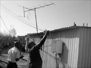 IN TROUBLE: A municipal official disconnects an illegal electricity connection at Barcelona Extension in Daveyton, Benoni. Pic. Dan Fuphe. © Sowetan.