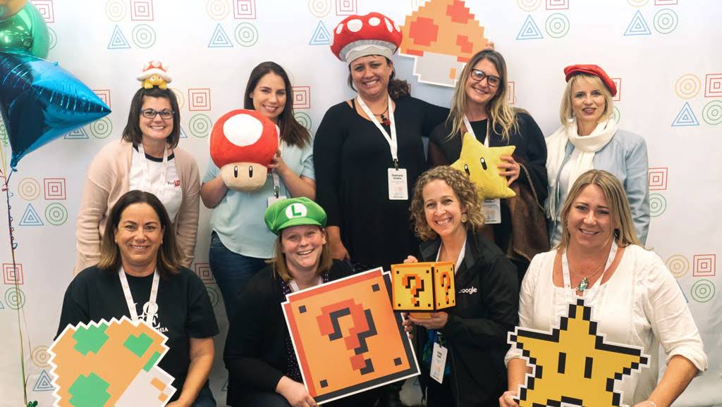Nine women are posing with Mario Kart accessories