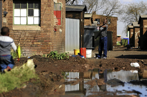 A man warns a toddler to be careful as he walks past a spot flooded at the Actonville hostel in Benoni, Ekurhuleni. The hostel has raw sewage overflowing into the walkways and hasn't seen basic service delivery in weeks.