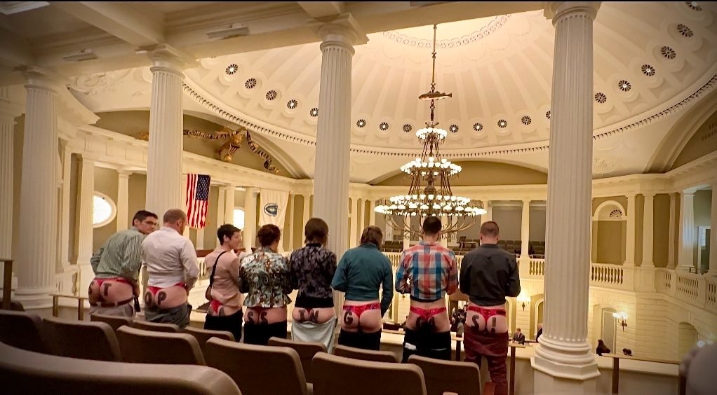 Rebels in red thongs bare their bottoms in the balcony of an official looking building