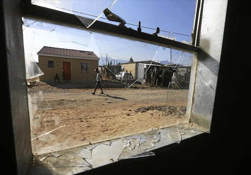 SHATTERED: An Avian Park resident walks past one of the nine house destroyed by residents furious about gang violence.