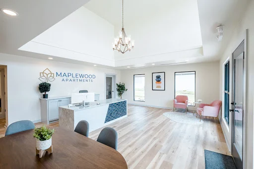 Maplewood clubhouse with vaulted ceilings, pink chairs, desk, table, wood plank floors