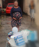 Dinika Rooy poses in front of all the gifts she received during her surprise drive-by and drop-off baby shower.